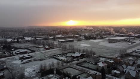 Drone-shot-revealing-sunrise-in-the-suburbs-of-Europe-covered-in-snow-in-winter
