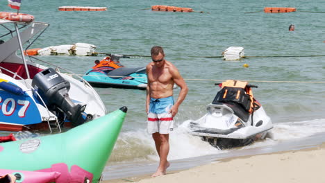 Man-is-seen-fixing-his-shorts-while-others-swimming,-mother-and-daughter-approaches-the-rushing-waves