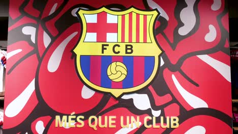 Insignia-Del-Equipo-Del-Club-De-Fútbol-De-Barcelona-Con-El-Fondo-Temático-De-La-Banda-Rolling-Stones-Visto-En-Las-Instalaciones-Del-Estadio-De-Fútbol,-Spotify-Camp-Nou,-Dentro-De-Su-Tienda-Oficial-De-Productos.