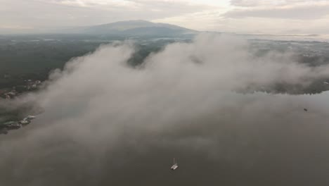 White-sailboat-anchored-in-middle-of-dulce-river-at-Guatemala,-aerial