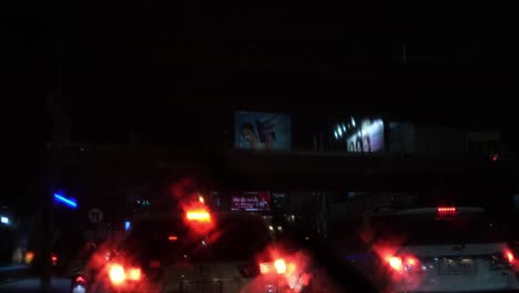 Water-is-prayed-on-the-windshield-to-clean-during-a-red-light-in-a-heavy-traffic-in-Bangkok-also-revealing-Billboards,-Thailand