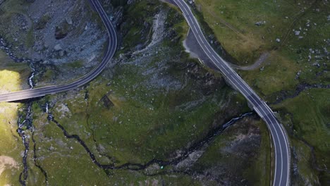 Forward-aerial-shot-of-rocky-mountain-road-with-stream