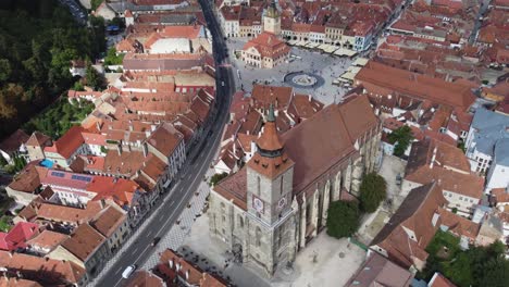 Backward-aerial-shot-of-Biserica-Neagra-showing-Brasov,-Romania