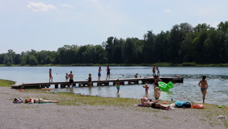 Children-And-Adults-Enjoy-Playing-And-Sunbathing-At-Kuhsee-Lake-In-Augsburg,-Germany