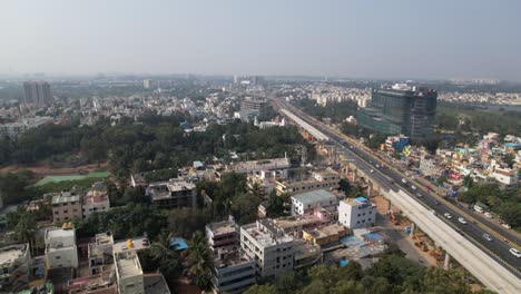 A-service-road,-quickly-moving-cars,-and-residential-and-commercial-buildings-on-an-expanding-Indian-highway-are-all-depicted-in-dramatic-aerial-footage