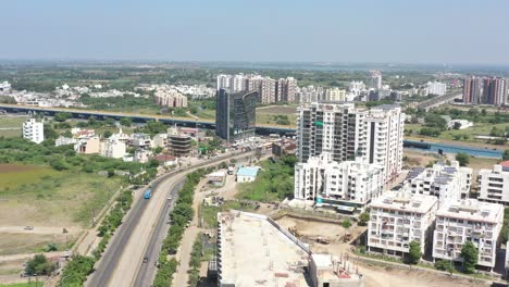 Cámara-De-Vista-Aérea-De-La-Ciudad-De-Rajkot-Delante-De-Madhapar-Chowkdi,-Que-Está-Cubierta-Por-Muchos-árboles