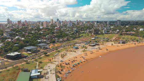 A-breathtaking-panoramic-side-view-captured-by-a-drone,-highlighting-the-picturesque-city-of-Posadas-and-its-scenic-Playa-El-Brete