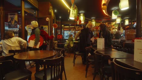 People-enjoying-the-autumn-weather-in-a-typical-french-coffee-shop,-indoor-view