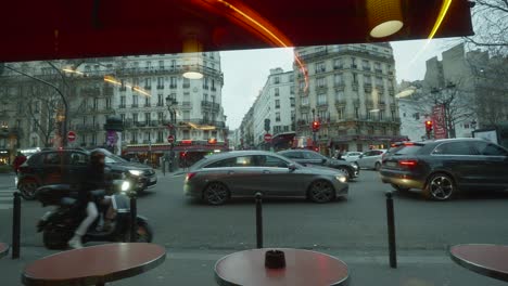Vista-En-Perspectiva-Detrás-De-La-Ventana-Del-Restaurante-Del-Tráfico-De-La-Ciudad-En-Un-Semáforo-En-Rojo-En-París