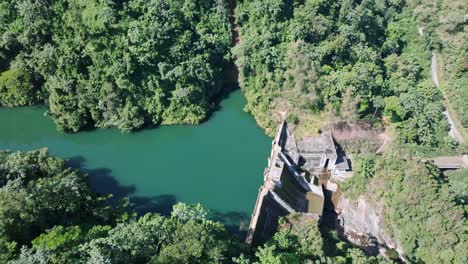 Artificial-lake-with-dam-in-the-Dominican-Republic,-aerial-orbit-power-plant