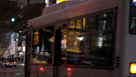 Bus-Traffic-in-Shibuya-at-Night-during-Rain,-Tokyo,-Japan