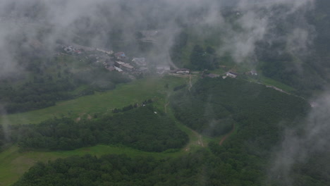 Drone-shot-overlooking-the-slopes-and-the-Shiga-Kogen-village,-foggy,-summer-day-in-Japan