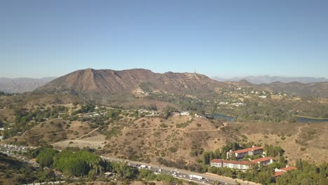 Slow-aerial-view-of-hills-and-desert-with-city-in-the-background-los-angeles