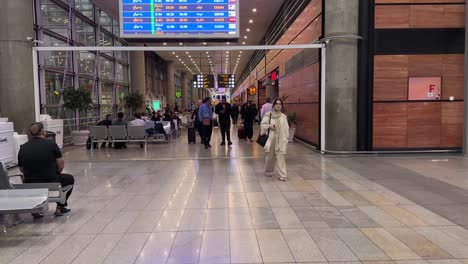 Tablero-De-Vuelo-Y-Gente-Caminando-Para-Facturar-El-Pasaporte-En-El-Aeropuerto-De-Teherán,-Irán,-Campo-Aéreo-Ika,-Mujer-Khomeini-Libre-De-Usar-El-Hijab-Preferido-Después-De-Luchar-Por-La-Libertad-Contra-La-Fuerza-Del-Gobierno-Para-Usar-Bufanda