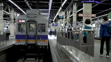 Personas-Que-Llegan-Y-Toman-El-Tren-Estacionado-En-El-Andén-De-La-Estación-De-Namba.