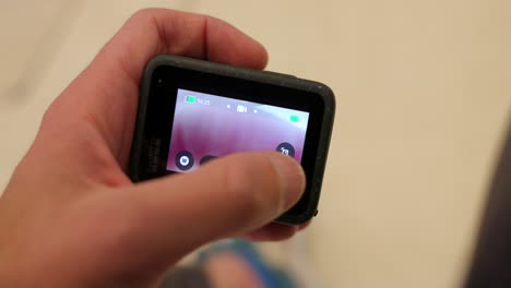 Close-Up-Shot-Of-Left-Hand-Holding-GoPro-Hero-12-And-Scrolling-Through-Settings-On-Back-Screen
