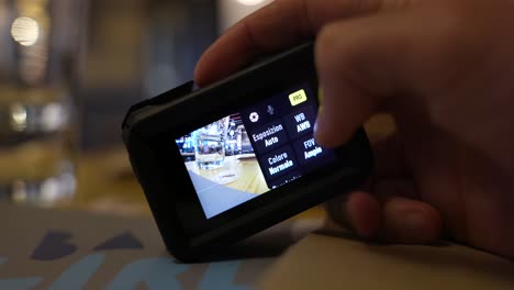 Close-Up-Shot-Of-Right-Hand-Holding-Osmo-Action-4-And-Scrolling-Through-Settings-On-Back-Screen