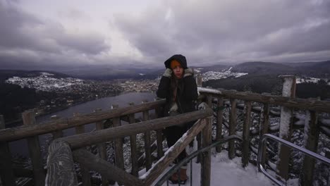 Young-woman-looking-out-over-Gerardmer-Lake-in-the-Vosges-Mountains-on-a-cold-snow-covered-morning