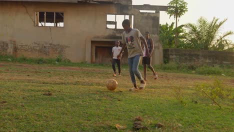 Ein-Junge-Gibt-Den-Ball-Einem-Anderen-Zu-Und-Dribbelt-Ihn-Durch-Einen-Jungen-Mit-Orangefarbenem-Hemd-Hindurch,-Scheitert-Aber,-Gemeinschaftsfußballplatz,-Kumasi,-Ghana