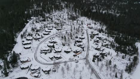 Drone-shot-of-a-small-cottage-village-by-a-slope-in-winter-