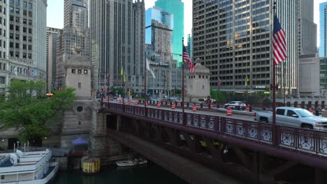 Chicago-River-with-a-boat-docked-and-a-bridge,-lined-by-American-flags-and-urban-skyscrapers