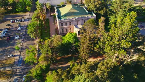 Drone-circling-the-garden-in-front-of-the-Palacio-Cousiño,-sunset-in-Santiago,-Chile