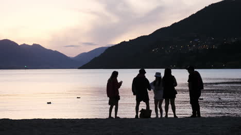 Junge-Erwachsene-Silhouetten-Tanzen-Und-Feiern-In-Queenstown-Am-Strand-Bei-Sonnenuntergang