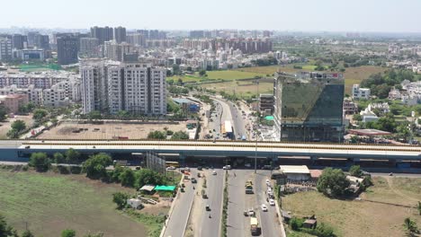 RAJKOT-CITY-AERIAL-VIEW-Dhole-camera-is-moving-over-the-bridge-where-a-big-black-bus-is-standing-at-the-bus-stop