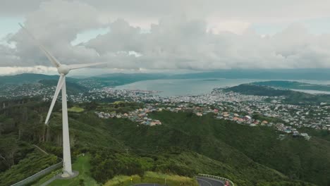 Reverse-aerial-flight-of-iconic-Brooklyn-wind-turbine-and-panoramic-landscape-views-of-capital-city-of-Wellington-in-New-Zealand-Aotearoa
