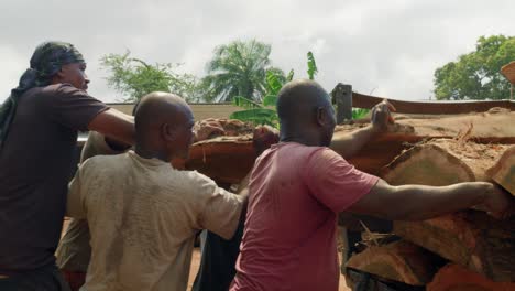 Group-of-sweaty-African-men-work-lift-and-push-logs-into-back-of-truck