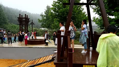 Chinese-group-of-people-playing-having-fun-swaying-swinging-standing-and-falling-on-wooden-suspended-swing-bridge-panoramic-view
