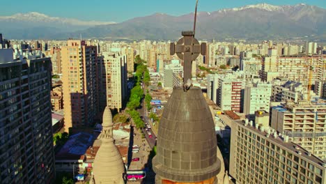 Ascending-drone-shot-with-the-black-copper-dome-with-the-cross-of-the-Sacramentinos-church,-Santiago-Chile