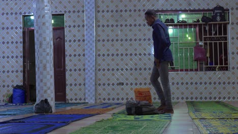 Side-view-of-man-bending-over-to-hold-knees-and-pray-head-down-in-mosque