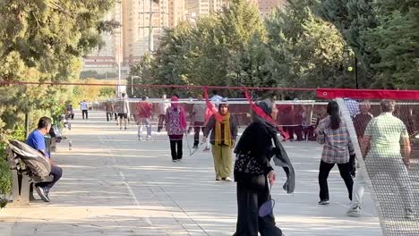 Iranische-Frauen-Spielen-Badminton-Auf-Einem-öffentlichen-Platz.-Stadtpark-Im-Iran,-Teheraner-Bezirk-Chitgar,-Innenstadt,-Kostenloser-Hijab,-Freiheitskampf,-Morgengymnastik,-Berglandschaft-Und-Leben-Der-Einheimischen,-Städtische-Hauptstadt