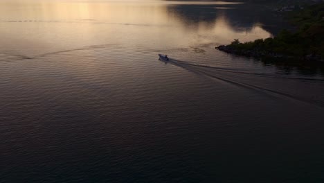 Speedboat-is-cruising-at-Lake-Atitlan-Guatemala-during-sunrise,-aerial