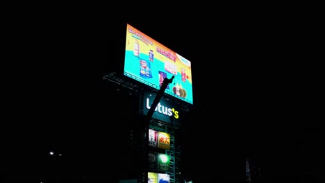 A-Lotus's-Super-Market-LED-Billboard-with-KFC,-MK,-Pizza-Company,-in-the-night-with-a-crane-boom-going-up,-Thailand