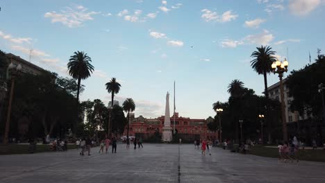 People-Walk-In-Plaza-De-Mayo-Landmark,-Buenos-Aires-City-Argentina-Presidential-Government\'s-Pink-House,-Casa-Rosada