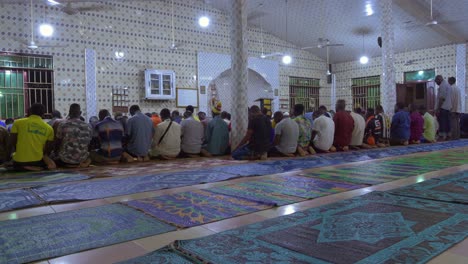 Angled-rear-view-of-African-people-kneeling-in-prayer-at-mosque