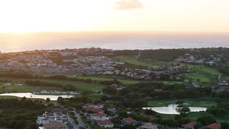 Panoramic-aerial-overview-around-golf-course-resort-looking-out-over-the-sea
