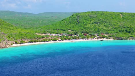 Panoramic-aerial-view-of-deep-blue-Caribbean-waters-to-crystal-clear-green-at-Playa-Porto-Mari