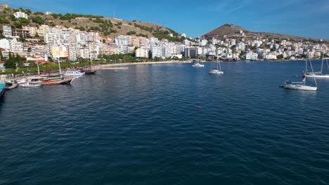 Boats-and-Yachts-Line-the-Pier,-Hotels-Nestle-Down-the-Hills,-Offering-Captivating-Sea-Views-in-the-Coastal-Bay-of-Saranda
