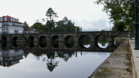 Roman-bridge-of-Aquae-Flaviae-in-Chaves,-Vila-Real,-Portugal-reflects-in-water-below