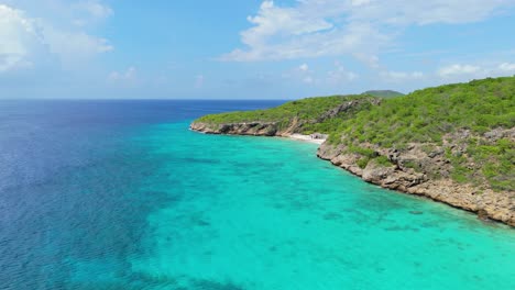 Drone-rises-above-Playa-hunku-with-Cas-Abou-behind-in-Curacao,-stunning-clear-day