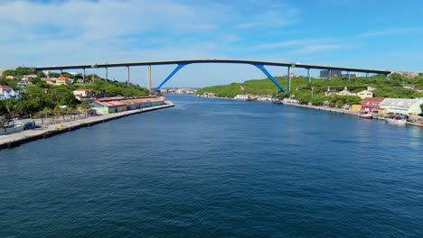 Aerial-wide-angle-view-of-Queen-Juliana-Bridge,-Willemstad-Curacao-from-river-below