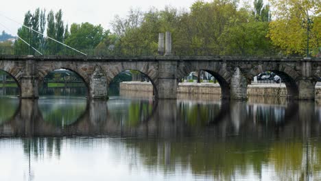 Establishing-side-view-of-roman-bridge-of-Aquae-Flaviae,-Chaves-Vila-Real-Portugal-reflecting-in-river