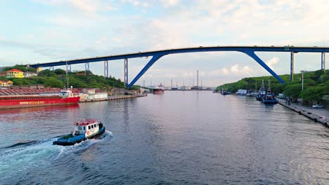 Tug-boat-drives-up-river-passing-under-Queen-Juliana-bridge-in-Willemstad-curacao
