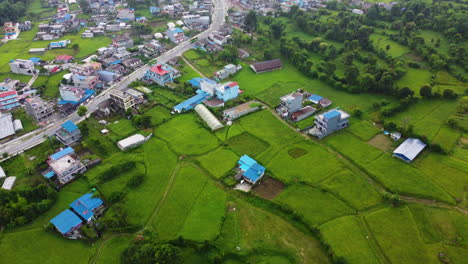Aerial-birds-eye-shot-of-Pokhora-City-with-farm-fields-and-traffic-on-main-road-during-cloudy-day---Tilt-up-shot---Nepal,Asia
