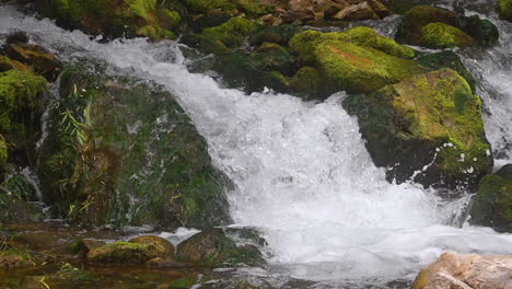 Water-Cascading-Through-Mossy-Rocks-In-The-Forest---Panning-Shot
