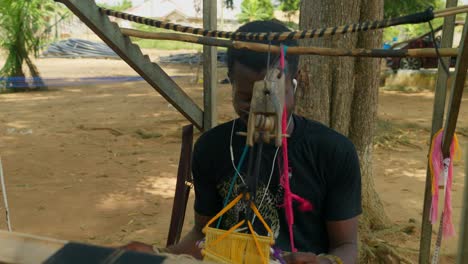 Bescheidener-Arbeiter-Aus-Ghana,-Der-Kente-Textilien-Webt-Und-Dabei-Musik-Hört
