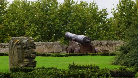Slow-tilt-up-behind-large-old-cannon-poking-out-of-parapet-in-Chaves-Vila-Real-Portugal